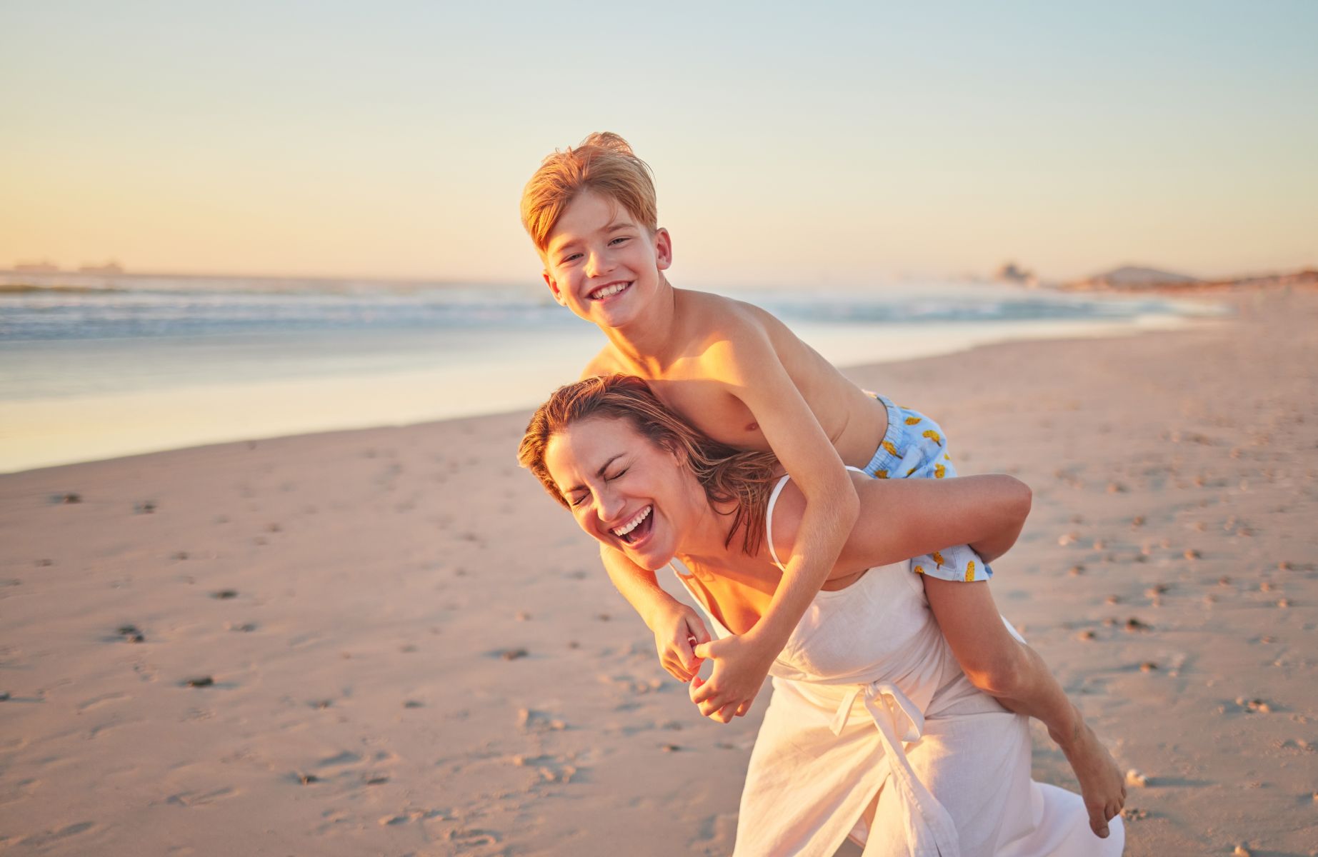 Mother and son having fun on warm sunset beach